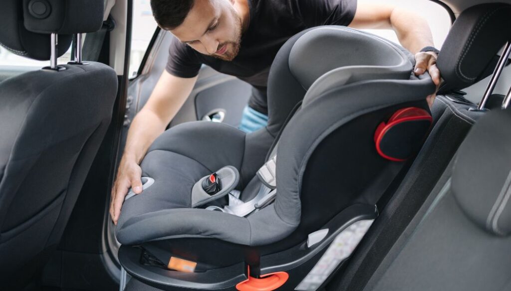 man installing baby car seat