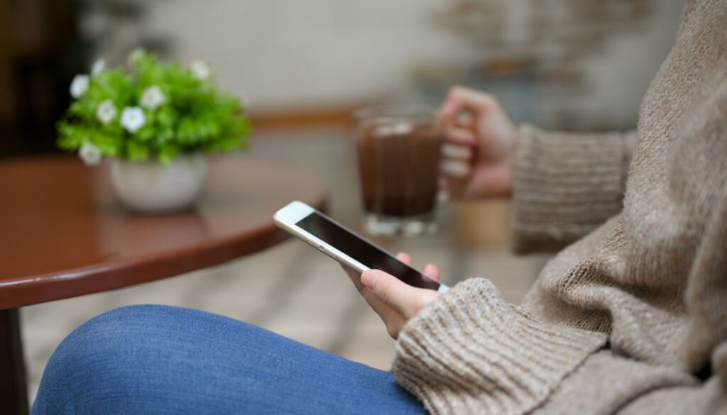 woman scrolling on her phone in a cafe