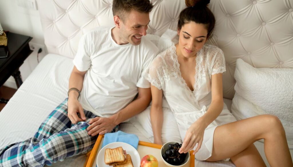 men and woman eating breakfast in bed