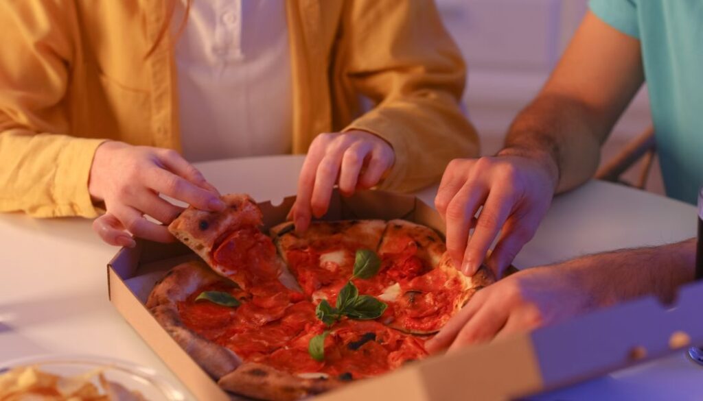 couple eating pizza at night in the kitchen