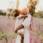 baby girl kissing mom in summer field