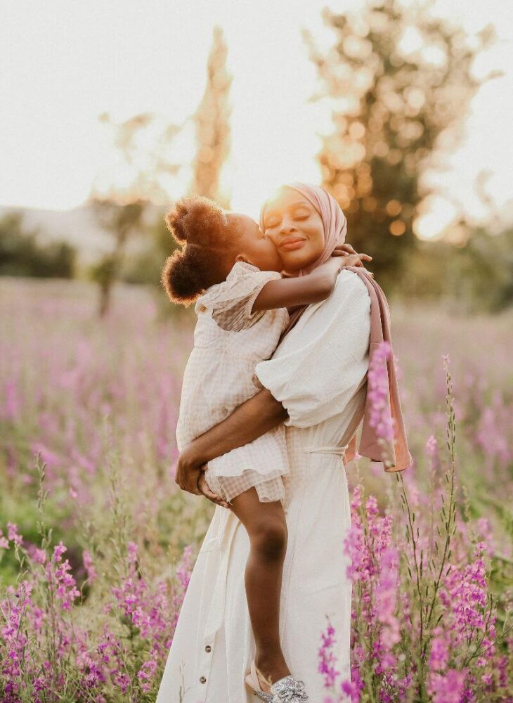 baby girl kissing mom in summer field