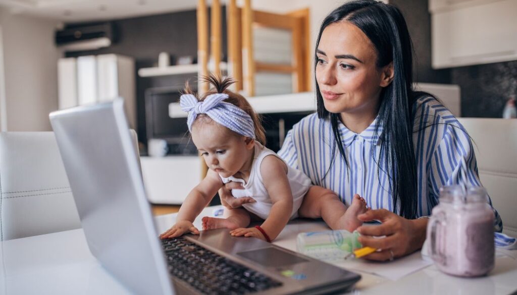 mom working on laptop carrying a baby
