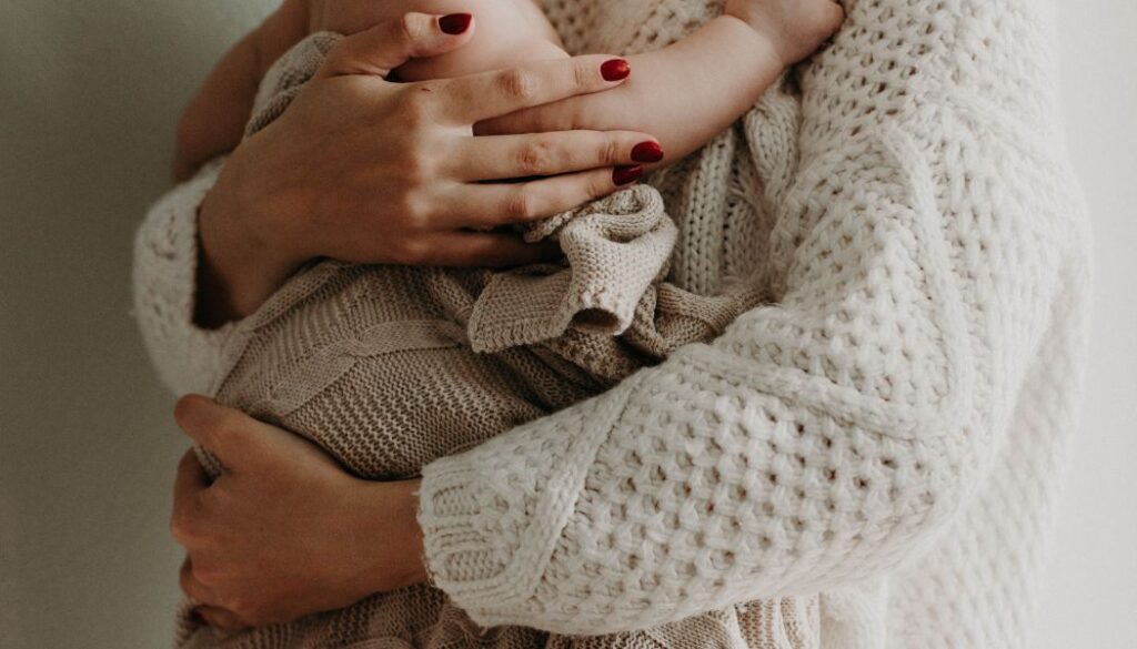 mom hugging her baby wrapped in a blanket