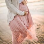 pregnant woman on a beach holding belly