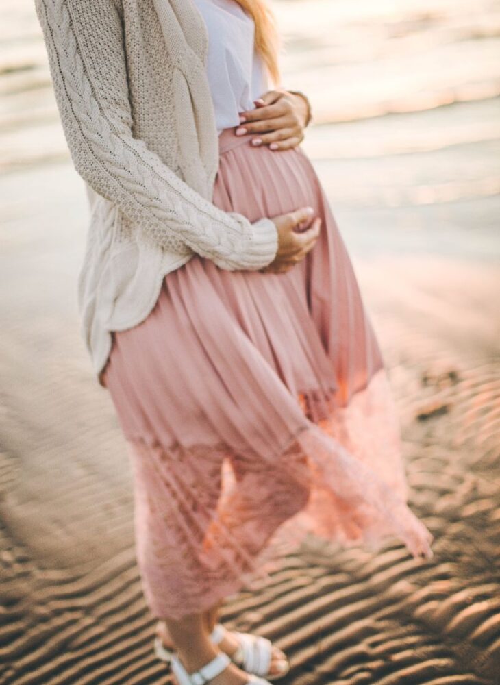 pregnant woman on a beach holding belly
