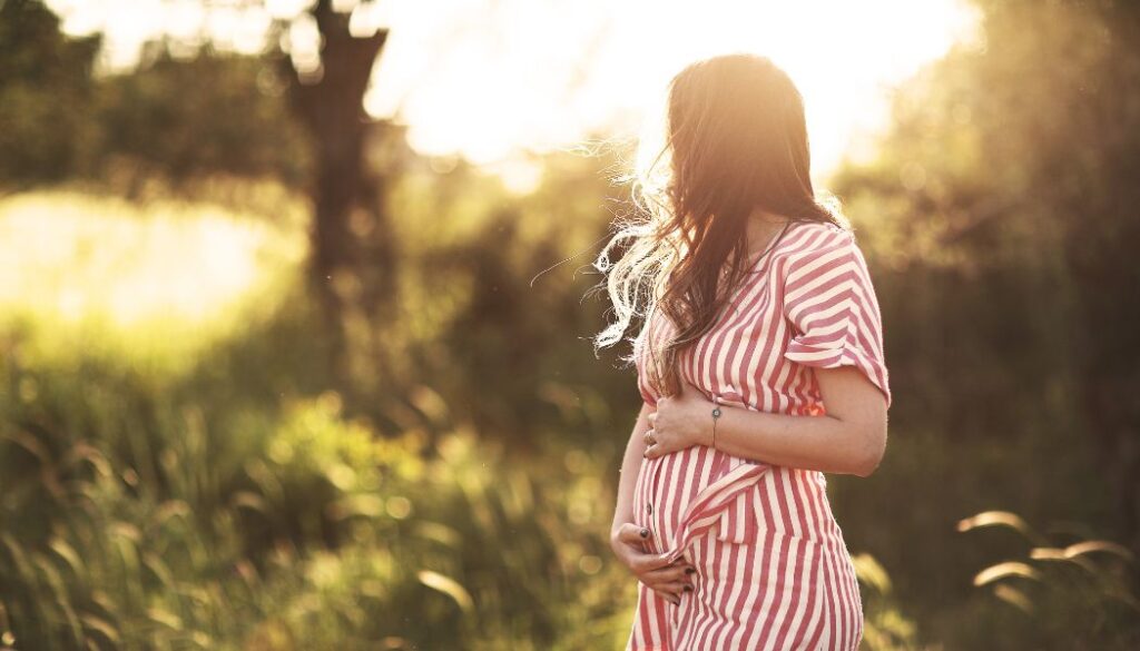 woman holding her pregnant belly in nature